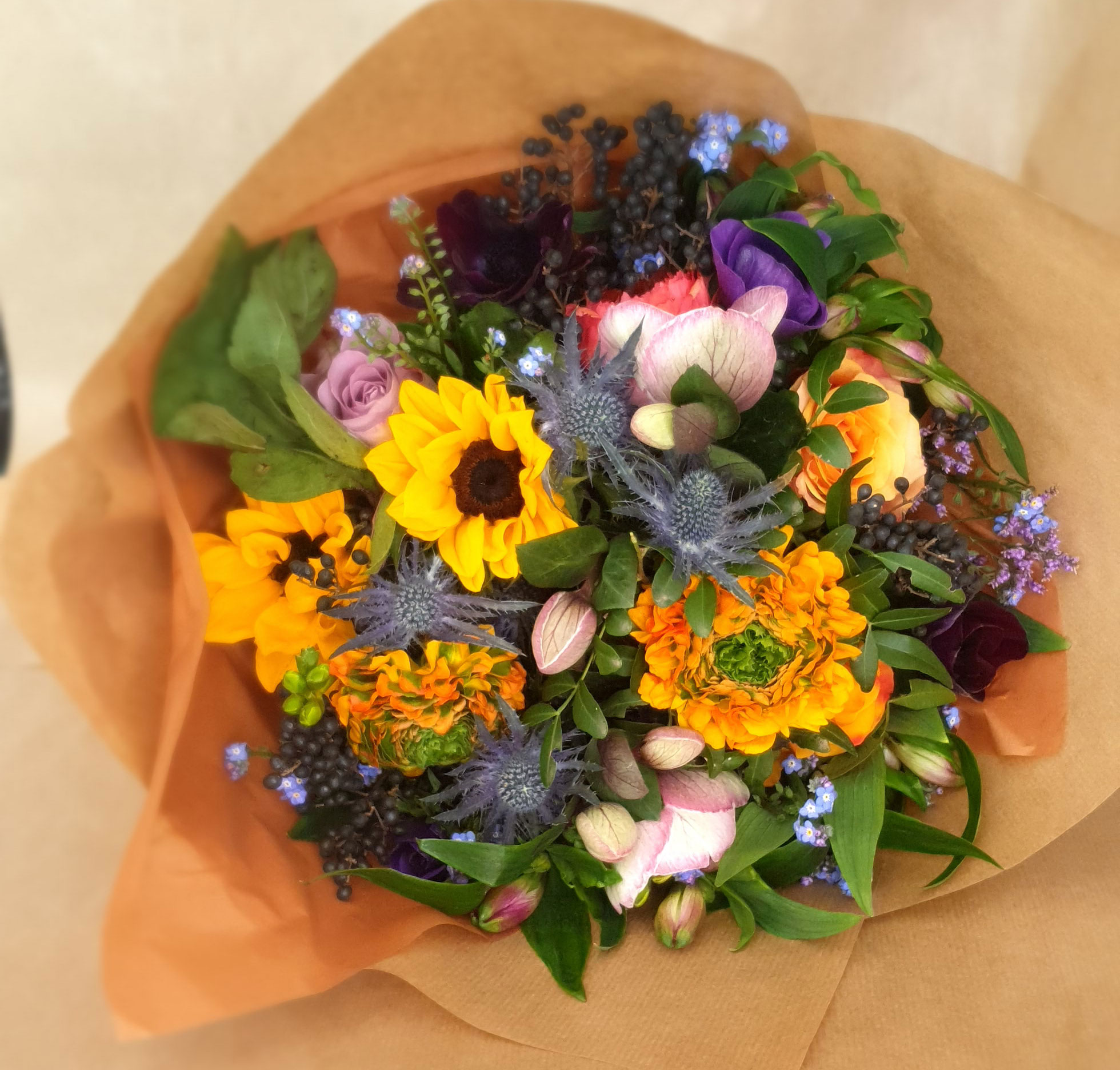 Hænder der holder mobiltelefon og tager billede af blomster